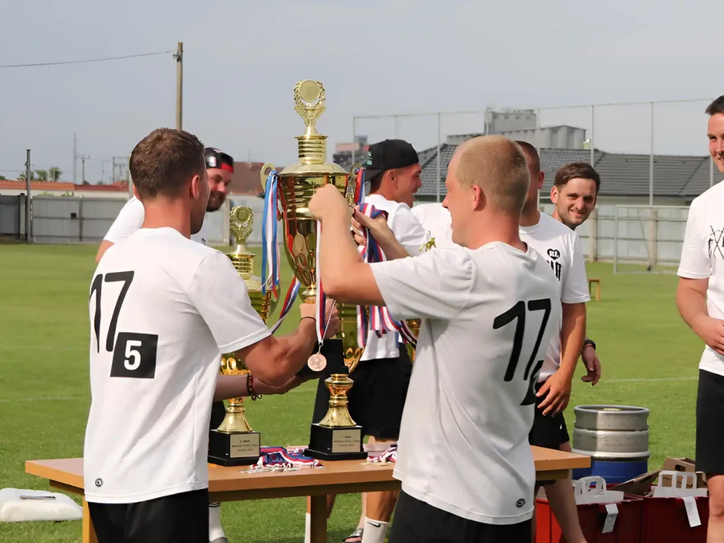 Fotbalisté si předávají vítězný pohár na Memoriálu Radka Lašáka